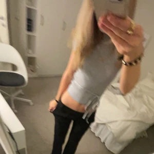 Grå ribbad topp med knytband - Snygg grå ribbad topp med korta ärmar och knytband i midjan. Perfekt för en stilren look. Använd 2 gånger så ja inte gillar den på mig.