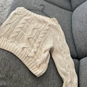 Vit stickad tröja - Säljer en supermysig vit stickad tröja med flätmönster. Perfekt för kyliga dagar och ger en härlig vinterkänsla. Tröjan har långa ärmar och en skön passform. Perfekt för både vardag och mysiga hemmakvällar!