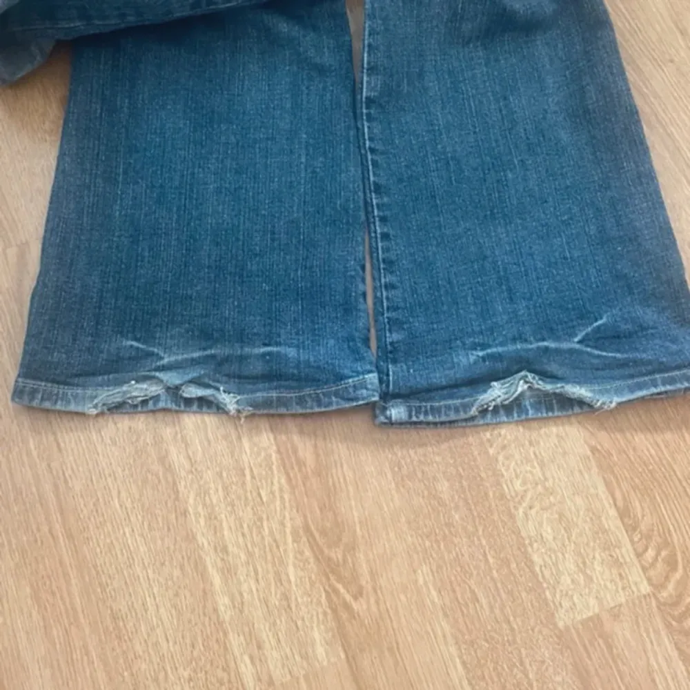 Säljer ett par snygga blå jeans med en cool. De har en klassisk femficksdesign och knappar på bakfickorna. Perfekta för hösten!. Jeans & Byxor.