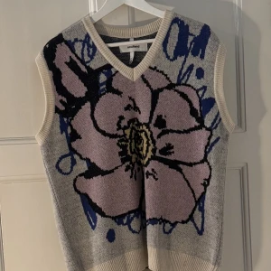 Soulland väst  - Snygg stickad väst med blommönster i rosa, blått och grått. Västen är i en mjuk och skön kvalitet. Perfekt till hösten!   Köpt för ca 2000 Kr Unisex  48 cm Axel till Axel och 64 cm längd  Skriv gärna ifall ni har några frågor :)