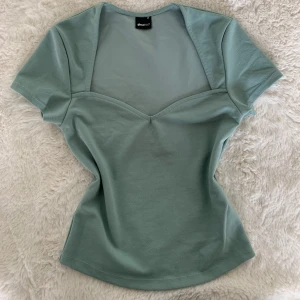 Turkos topp. Urringad topp. Kortärmad T-shirt  - Oanvänd topp från Gina💕. Den har en v-ringad design och korta ärmar! Bra skick  
