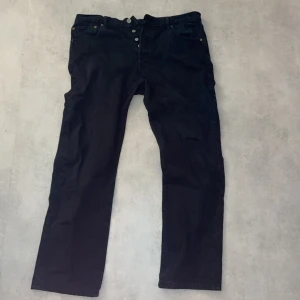Svarta jeansbyxor från Levi's - Säljer ett par svarta jeansbyxor från Levi's i bra skick. De har en klassisk straight passform. Byxorna har knappar istället för dragkedja. W-36 L-34