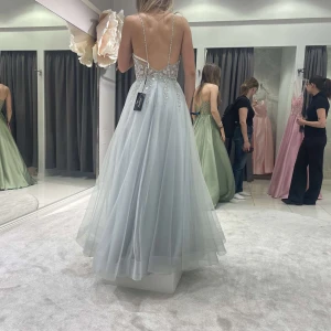 Ljusblå balklänning från Zazabella - Säljer en fantastisk ljusblå balklänning från Zazabella med glittriga detaljer och en vacker spetsdesign på överdelen. Klänningen har en öppen rygg och smala axelband, perfekt för bal eller fest. Den är i långt utförande och ger en elegant look. Perfekt för att glänsa på speciella tillfällen! storleken är 32 men passar 34/36. Ovh 550€