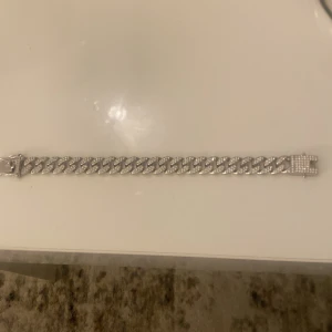 Silverfärgat armband med glittriga detaljer - Säljer ett snyggt silverfärgat armband med glittriga detaljer. Armbandet har en robust kedjedesign och är perfekt för att ge lite extra bling till din outfit. Passar både till vardags och fest. Lätt att matcha med andra smycken!