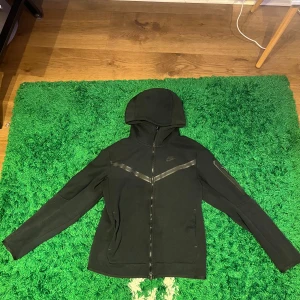 Nike Tech Fleece zip hoodie - Svart Nike Tech fleece zip i storlek S, det finns en liten reva/hål på högra fickan men inget som märks. 
