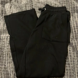 Svarta låga mjukisbyxor - Säljer ett par svarta låga  mjukisbyxor i bra skick. De har en bekväm passform med resår och snörning i midjan. Perfekta för en avslappnad dag hemma eller en promenad i parken. Storleken är inte angiven men de ser ut att vara unisex. Passar till både höst och vinter.