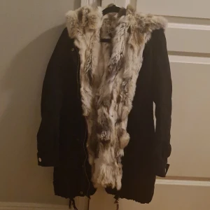 Svart jacka med päls från On Parle de Vous - Säljer en snygg svart jacka från On Parle de Vous med mjuk päls i beige och bruna toner. Jackan har en dragkedja framtill och är perfekt för höst och vinter. Den är i mycket bra skick och passar perfekt för kyliga dagar. 🖤