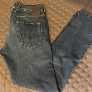 Blå jeans från Replay - Säljer ett par snygga blå jeans från Replay i modellen Anbass. De har en slim fit och är i bra skick med en cool tvättad look. Perfekta för både vardag och fest! 🕺w33 L32
