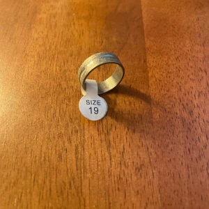 Silverfärgad ring i storlek 19 - Snygg och stilren ring i silverfärg, storlek 19. Perfekt för både vardag och fest. Den har en enkel men elegant design som passar till alla outfits.