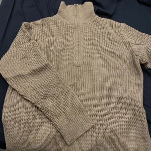 Beige stickad tröja med dragkedja - Säljer min mans mysiga, beigea stickade tröja med hög krage och dragkedja framtill. Otroligt mjuk o varm med lite tajtare nertill för en super snygg passform!