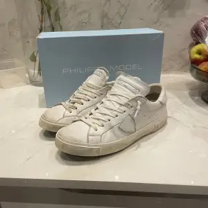 Tjena ! Säljer ett par vita sneakers från Philippe Model i bra skick. De har en klassisk design och är perfekta för vardagsbruk. Skorna är tillverkade i skinn och har en bekväm passform. Perfekta för både vår och sommar! Skoboxen till skorna tillkommer självklart också,  Kontakta för fler frågor eller bilder