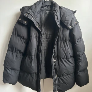 Vinterjacka - Svart vinterjacka med stor luva och använd ett fåtal gånger. Väldigt varm jacka som knäpps med dragkedja och knappar. Skulle säga att den funkar som M också. 