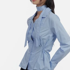 Brand New Korean Sleek Buttoned Stripe Blouse  CS420🐥 - Säljer en superfin blå randig blus från Koreanska med knytband runt halsen. Den har långa ärmar och en snygg passform som ger en elegant look. Perfekt för både vardag och fest! 💙Model is wearing size S/M and the color Blue.  Height : 5'5" | 166cm / Top : XS / Bottom : S (25 inch)