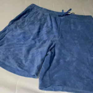 Blå frottéshorts från Polo Ralph Lauren - Säljer ett par superbekväma blå shorts i frotté från Polo Ralph Lauren. Dessa frittéshorts stämmer inte helt med storleken där den perfekta storleken för dessa shorts är S men fungerar även i XS. Perfekta för sommaren med en avslappnad passform och snörning i midjan. De har en liten Polo-logga på benet och är i mycket bra skick. Perfekta för en chill dag vid stranden eller hemma! Ordinare pris 800kr