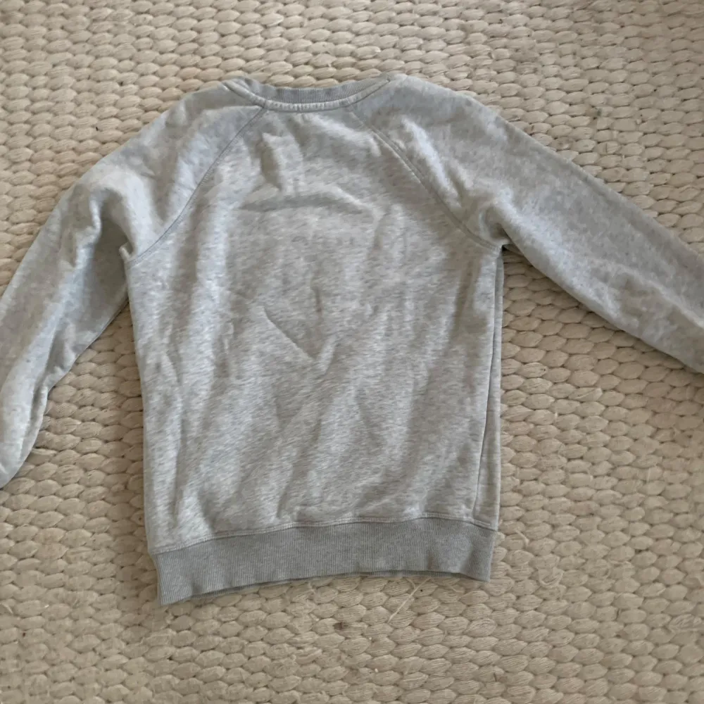 Säljer en snygg grå sweatshirt från GANT i storlek XS. Den har ett klassiskt tryck på bröstet och är supermjuk och bekväm. Perfekt för en avslappnad stil eller att mysa i hemma. Tröjan är i bra skick och passar perfekt till jeans 🤩. Tröjor & Koftor.