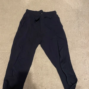 Mörkblåa mjukisbyxor från Skill - Säljer ett par svarta mjukisbyxor från Skill i storlek 158/164 (S) Byxorna har en bekväm passform med resår i midjan och snörning för justering. Perfekta för en avslappnad dag hemma eller lätt träning. De är i bra skick och redo för en ny ägare!