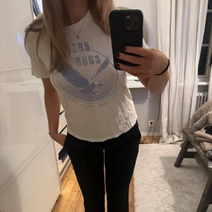 Vit t-shirt med blått tryck - Säljer denna vita t-shirt med snyggt blått tryck av en örn. 