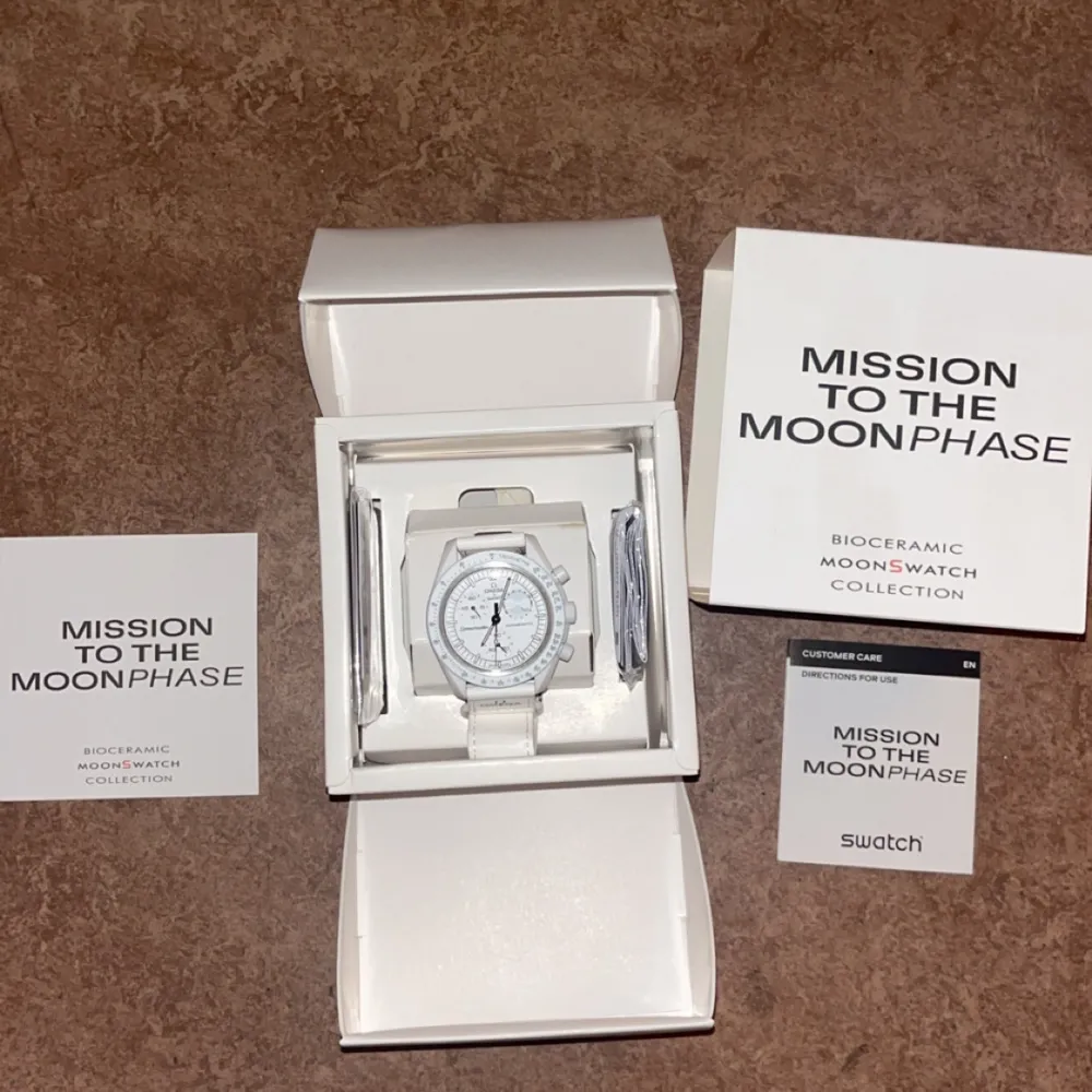 Säljer en snygg vit klocka från Swatchs Bioceramic Moonswatch Collection, 'Mission to the Moonphase'. Klockan har en stilren design med vit urtavla och detaljerade markeringar. Perfekt för både vardag och fest! Kommer i originalförpackning.. Accessoarer.