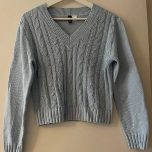 Ljusblå stickad tröja med kabelmönster - Säljer en superfin ljusblå stickad tröja med kabelmönster. Den har en v-ringad hals och långa ärmar, perfekt för kyliga dagar. Tröjan är i mycket bra skick och passar perfekt till både vardag. Ett måste i garderoben! 💙