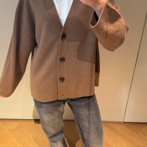 Brun kofta med knappar - Säljer en mysig brun kofta i normal passform från arket. Den har stora knappar framtill och långa ärmar, perfekt för höst och vinter. Koftan är i bra skick och passar både till vardags och lite finare tillfällen. Koftan är också i 75% kashmir och 25% ull ! Koftan är i storlek L men passar personer som både använder M och S ✨Har använt ungefär två gånger ! 