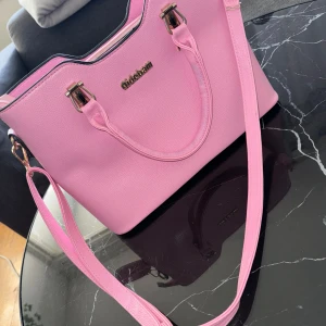 Rosa axelväska med matchande plånbok - Säljer en superfin rosa axelväska i syntetmaterial med matchande plånbok. Väskan har guldfärgade detaljer och en praktisk dragkedja. Perfekt för både vardag och fest! 💖