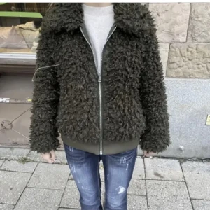 Svart teddyjacka med dragkedja - Mysig svart teddyjacka perfekt för höst och vinter. Den har en dragkedja framtill och långa ärmar. Jackan är i bra skick och passar både till vardags och lite mer avslappnade tillfällen. Perfekt för att hålla sig varm och stilren! Köpt här på plick.