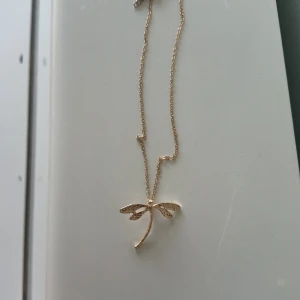Guldfärgat halsband med trollslända - Säljer ett superfint guldfärgat halsband med en trollsländeberlock. Kedjan är tunn och elegant, perfekt för både vardag och fest. Berlocken är detaljerad och ger en fin touch till din outfit. Köp direkt eller ge prisförslag 💛