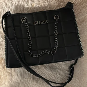 Svart Guess väska  - Säljer min fina Guess väska! Väldigt praktiskt och rymlig. Knappt använd så ny skick🥰 hör gärna av er om ni vill ha fler bilder eller har funderingar🥰