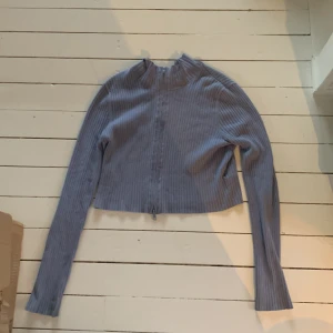 Grå ribbad kofta från Monki - Säljer en snygg grå ribbad kofta från Monki i storlek M. Den är croppad och har långa ärmar. Perfekt för höst och vår! Koftan är i nyskick och passar både till vardags och fest. Den är gjord av ett mjukt och bekvämt material som håller dig varm och stilren.