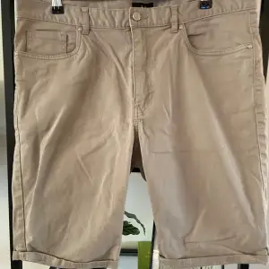 Säljer ett par snygga beige shorts från H&M. De är i storlek 34 (herr M) och har en klassisk femficksdesign. Shortsen är gjorda av bomull och har en bekväm passform. Perfekta för sommaren!