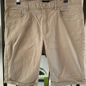 Beige shorts från H&M - Säljer ett par snygga beige shorts från H&M. De är i storlek 34 (herr M) och har en klassisk femficksdesign. Shortsen är gjorda av bomull och har en bekväm passform. Perfekta för sommaren!