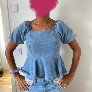 Blå jeansblus med puffärmar - Säljer en superfin blå jeansblus, Blusen har en peplumdesign som ger en snygg siluett och är perfekt för både vardag och fest. Den är i bra skick och passar perfekt till ett par jeans eller kjol. 💙storlek xxs, men passar mig som bär xs/s!