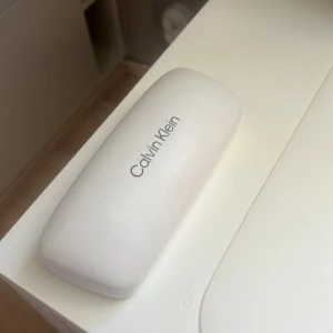 Calvin Klein glasögonfodral  - Vitt glasögonfodral från Calvin Klein med svart sammet på insidan. Använt o därav lite slitet men ändå bra skick, inte trasigt elr så. Säljer då inte används/behövs. KOLLA MIN PROFIL 💕