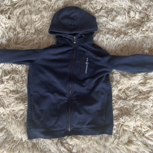 Sailracing zip hoodie - Varan är i bra skick med inget som är förstört. Storleken på den är 170. Det är en lite tjockare tröja så den är bra nu när det börjar bli höst och funkar bra på vintern också. Jag säljer den för den är för liten. 