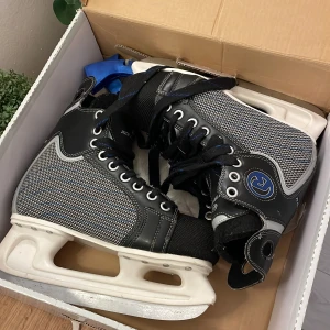 Svarta ishockeyskridskor från Revolution - Säljer ett par svarta ishockeyskridskor från Revolution i storlek 39. Skridskorna kommer med ett par blåa skydd för skenorna och är perfekta för vinterns alla isäventyr! Dem kostar 449kr och är som nya men säljer dem nu för mindre än halva priset.🏒❄️