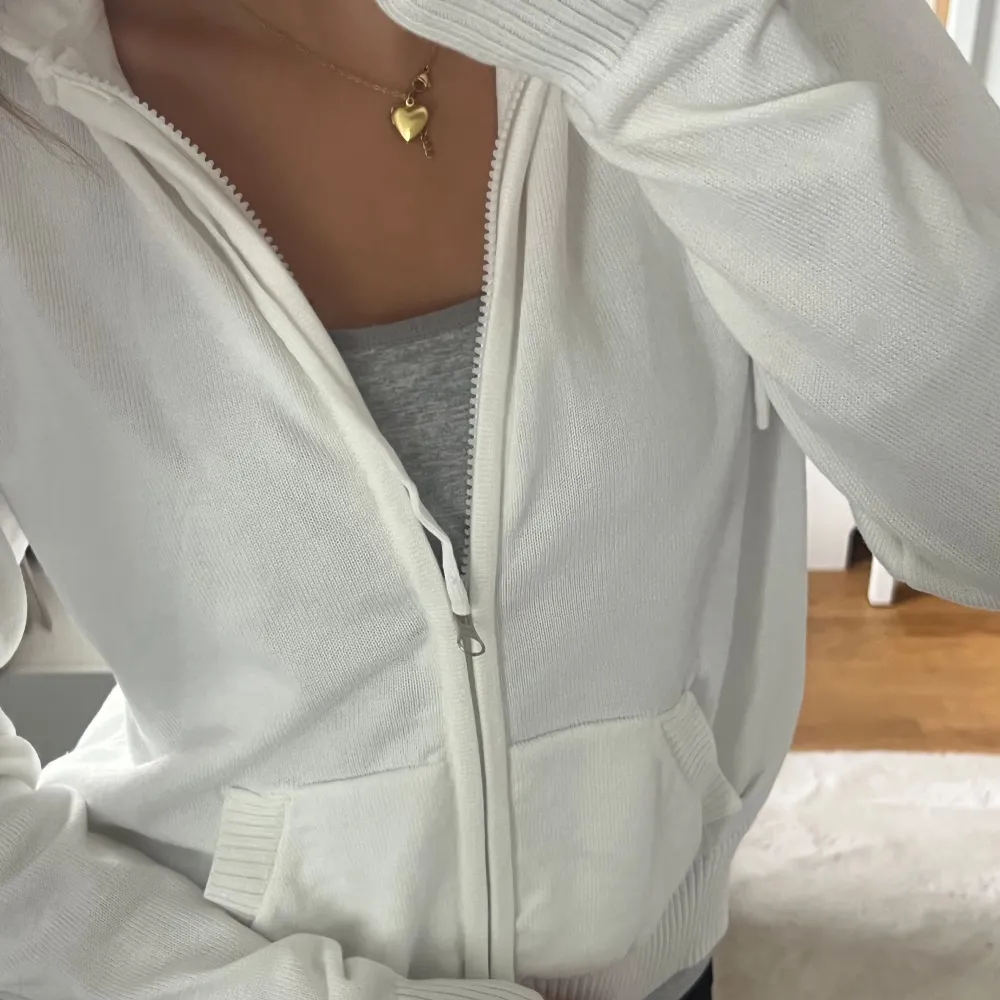 Säljer en vit zip-up hoodie i storlek S. Den är supermjuk och bekväm, perfekt för vardagsbruk. Den har en dragkedja framtill och två fickor. Ärmarna är långa med ribbade muddar. Passar perfekt till höst och vår!. Tröjor & Koftor.