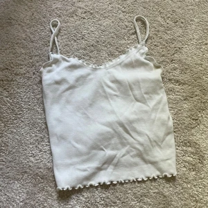 Vit linnetopp från Gina Tricot - Säljer en söt vit linnetopp från Gina Tricot.  den har volangdetaljer längs kanterna. Toppen är i bra skick säljer för den är för liten