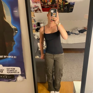 Gröna cargopants - Säljer ett par gröna cargopants. De är lågmidjade och har en lös passform. Byxorna har flera fickor på sidorna och är perfekta till ett svart linne eller en basic t-shirt. De är i bra skick och passar perfekt för hösten!