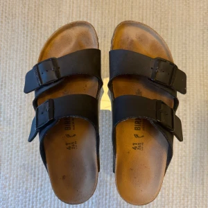 Svarta sandaler från Birkenstock - Säljer ett par svarta sandaler från Birkenstock i storlek 41 och modellen Arizona. Sandalerna är i fint skick!