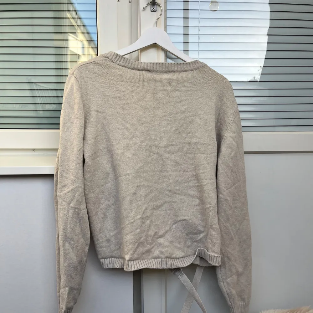 Säljer en superfin beige omlottkofta från Gina Tricot i storlek M. Den är stickad och har långa ärmar med ribbade kanter. Perfekt för höst och vår när du vill ha något mysigt men ändå stilrent. Koftan har knytband i midjan för en snygg passform. 🧥✨. Tröjor & Koftor.