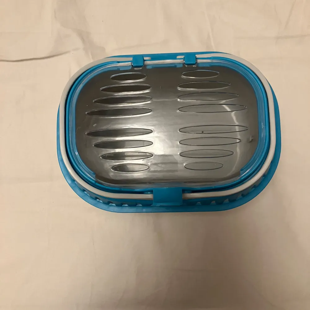Säljer en praktisk transportbur i blått och vitt. Perfekt för smådjur eller som en liten förvaringslåda. Den har en genomskinlig topp med ventilationshål och ett säkert lås. Enkel att bära och rengöra.. Muu.