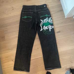 Säljer ett par svarta jeans från Ecko Unltd med cool graffiti-design i grönt och vitt på baksidan. Bra skick och har baggy passform. Passar mig som är 169 cm lång💗