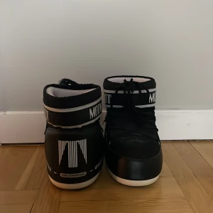 Svarta Moon Boots - Säljer mina svarta Moon Boots i bra skick, bara använde en vinter!  De är perfekta för vintern. Skorna har en cool och unik stil med snörning och en bred vit sula. Säljer eftersom de är för små!💕ny pris 1999kr
