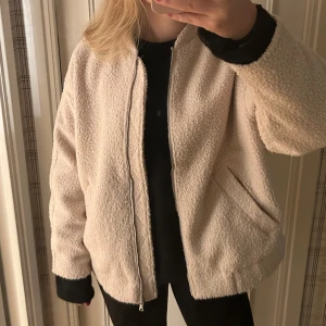 Beige teddyjacka - Mysig beige teddyjacka i oversized stil med dragkedja framtill. Perfekt för höst och vår, den har långa ärmar och är superbekväm. Jackan är i mycket bra skick och passar perfekt för en avslappnad look. Stilen på jackan liknar även en bomberjacka😘
