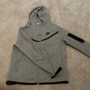 Nike tech grå  - Jag säljer en grå Nike tech i barn storlek 147-158cm Väldigt bra skick. Ser ny ut och är använd fåtals gånger. 