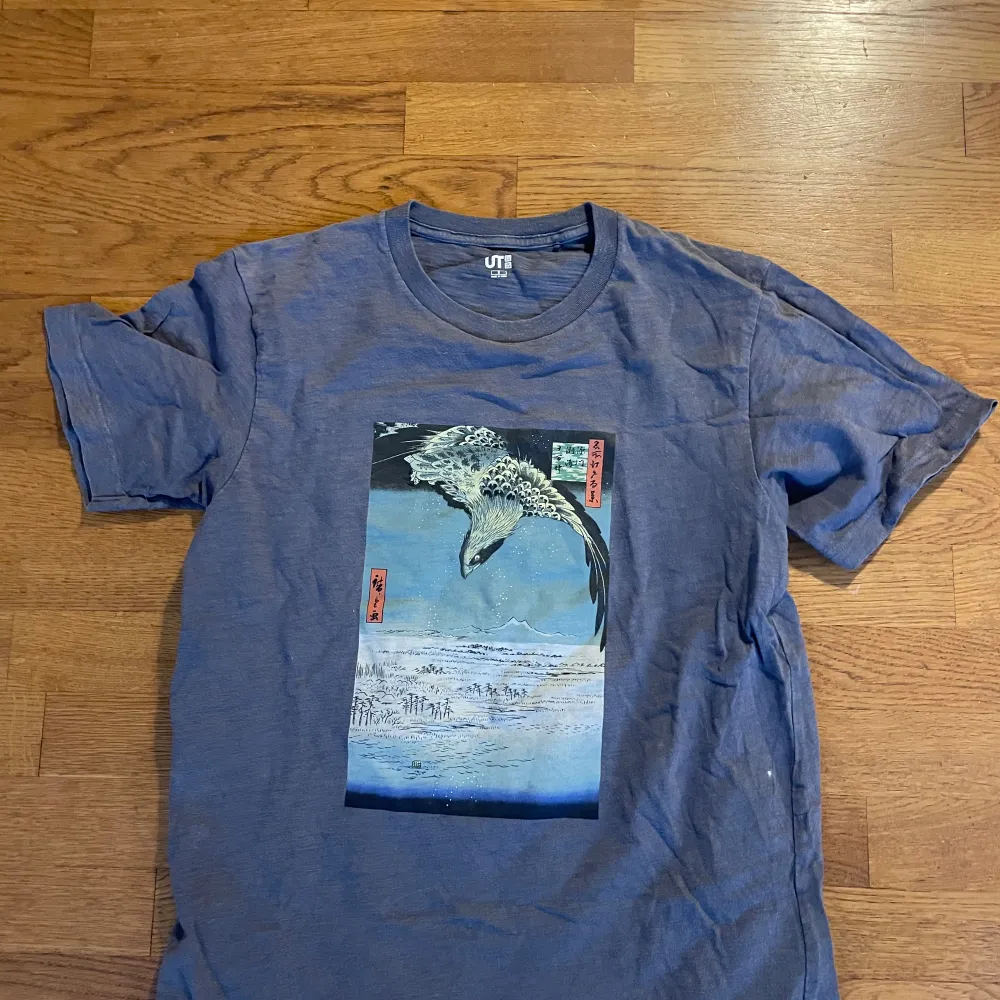 Säljer en blå t-shirt från Uniqlo med ett coolt konstmotiv av en fågel på både fram- och baksidan. T-shirten är i bra skick och perfekt för vardagsbruk. Den är gjord av mjukt material och har en normal passform. Urtvättat men annars okej skick. T-paidat.
