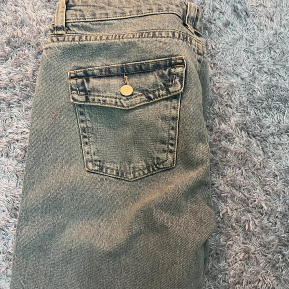 Säljer ett par snygga grå jeans från Gina i storlek 42. De har en bootcut-stil som ger en retro vibe och är perfekta för både vardag och fest. Jeansen är i nytt skick med etikett kvar. De har en klassisk femficksdesign och stängs med dragkedja och knapp. . Jeans & Byxor.