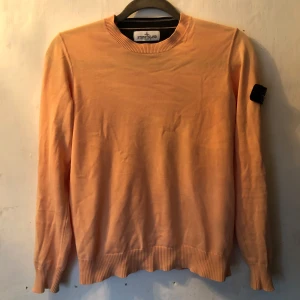Persikofärgad tröja från Stone Island Junior - Säljer en snygg persikofärgad tröja från Stone Island Junior. Den har en klassisk rund hals och långa ärmar. Tröjan är i bra skick och har den ikoniska Stone Island-loggan på ärmen. Perfekt för både vår och höst! Funkar till 146-152 och nypris på 1250kr.
