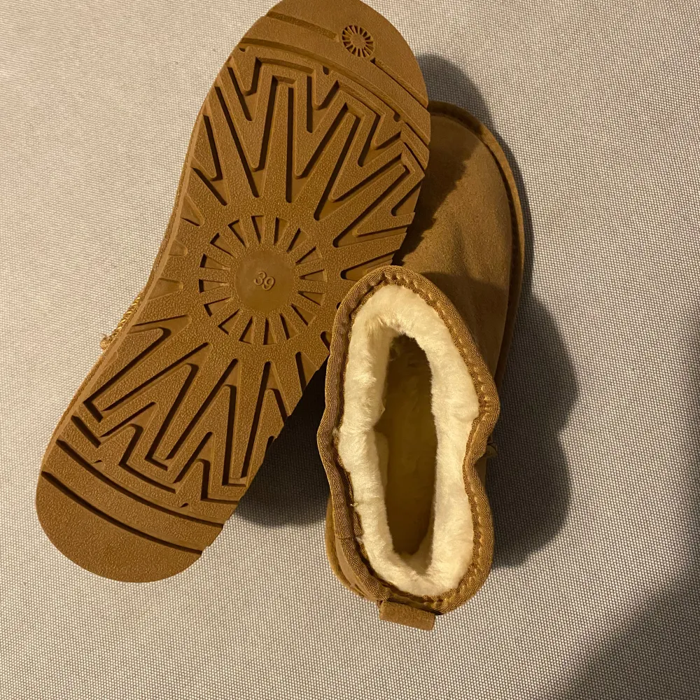 Uggs-liknande (mini) som är lite små i storleken. Jag har 2 par likadana (upplagt i varsin annons) som båda är storlek 38 (fast det står stl 39 på dem). Beige.   Superfina och sköna! Helt oanvända eftersom de var för små för mig/oss. . Skor.