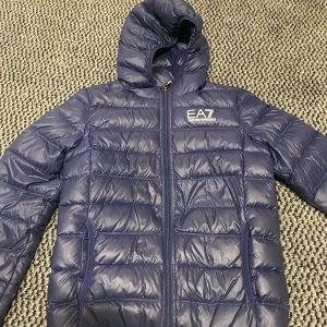 EA7 dunjacka - Blå dunjacka från EA7. Har ett litet hål men den syns inte